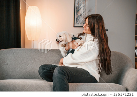 Sitting on the sofa. Beautiful woman is with maltese dog is at home Sitting on the sofa. Beautiful woman is with maltese dog is at home 126171221
