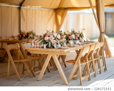 Rustic outdoor banquet with wooden chairs, seasonal flowers, and sunlight, perfect for events. Rustic outdoor banquet with wooden chairs, seasonal flowers, and sunlight, perfect for events. 126171351