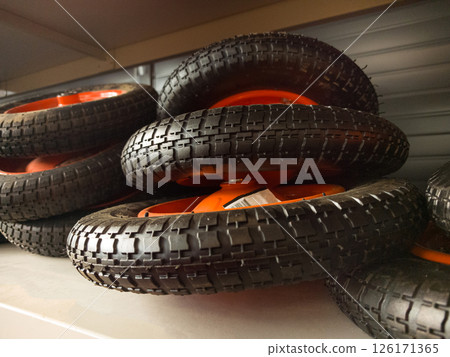 Collection of black rubber wheels stacked on a shelf in a workshop Collection of black rubber wheels stacked on a shelf in a workshop 126171365