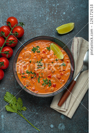 Brazilian traditional dish moqueca de camarao with shrimps, tomatoes, peppers, and lime in a bowl top view 126172618