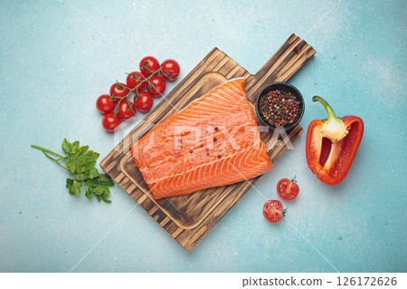 Fresh raw salmon fillet with cooking ingredients on wooden board top view on light blue background 126172626