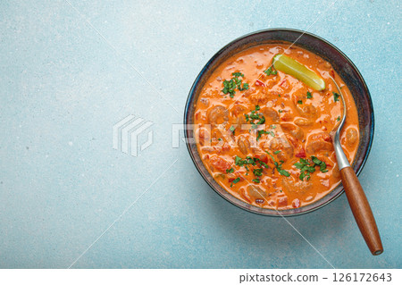 Brazilian traditional dish moqueca de camarao with shrimps, lime, peppers, and cilantro is served in a bowl on light blue background top view, space for text 126172643