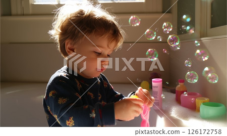 Child enjoys a sunny afternoon creating bubbles in a bright bathroom filled with colorful toys and soap 126172758