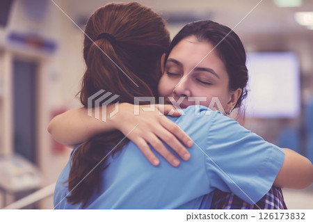 Young patient in a hospital hallway embraces her nurse, symbolizing care and hope in healthcare 126173832
