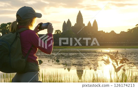 Young Woman Capturing the Sunrise at Angkor Wat with Her Smartphone 126174213