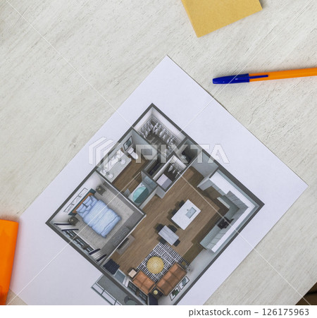 Layout of the small, furnished apartment printed on the sheet of paper placed on the desk Layout of the small, furnished apartment printed on the sheet of paper placed on the desk 126175963