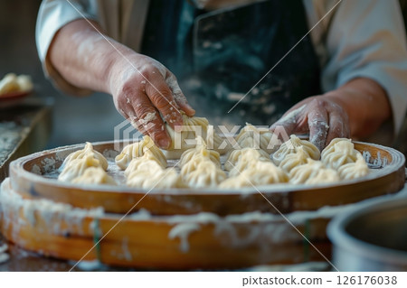 Street food vendor carefully placing freshly made dumplings onto a steamer, preparing for the next hungry customer 126176038