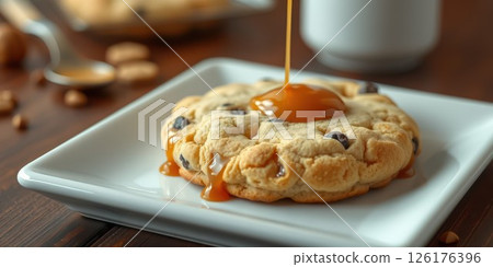 Chocolate chip cookie topped with warm caramel sauce on a white plate with wooden background Chocolate chip cookie topped with warm caramel sauce on a white plate with wooden background 126176396