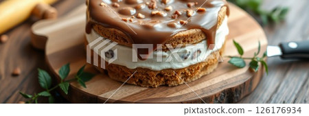 Delicious layered dessert with creamy filling and caramel topping on a wooden board in a cozy kitchen setting 126176934