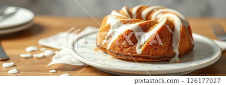 Delicious bundt cake served on a rustic wooden table with white icing drizzled on top during a cozy afternoon Delicious bundt cake served on a rustic wooden table with white icing drizzled on top during a cozy afternoon 126177027