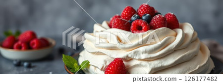 Meringue dessert topped with fresh raspberries and blueberries on a rustic table 126177482