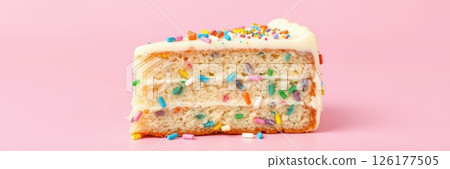 Colorful cake slice with frosting and sprinkles on a pink background showcasing dessert art 126177505