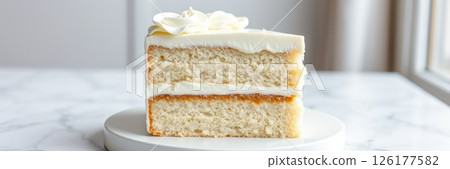 Deliciously layered vanilla cake with cream frosting showcased on a marble surface near a bright window 126177582