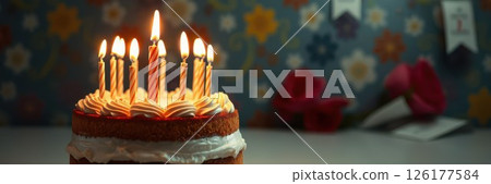 Celebrating a special occasion with a decorated cake and glowing candles in a festive setting 126177584