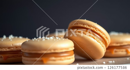 Delicious golden macarons arranged elegantly on a wooden surface highlighting their smooth texture and creamy filling 126177586