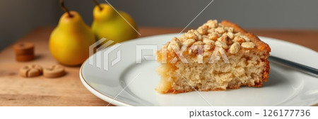 Delicious pear cake with crunchy topping served on a white plate beside fresh pears 126177736