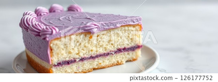 Delicious purple frosted cake with layers of cream and sponge on a white plate against a light background 126177752