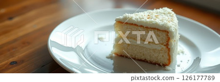 Delicious slice of coconut cake served on a white plate with a wooden table background 126177789
