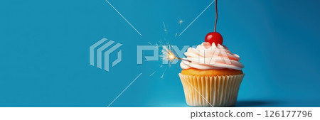 Cupcake topped with creamy frosting, cherry, and sparkler on blue background for celebration moments 126177796