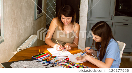Happy mother and daughter drawing together at home. Family bonding and joyful moments. Childhood memories, love, and art. Perfect for concepts of parenting, education, and quality family time. Happy mother and daughter drawing together at home. Family bonding and joyful moments. Childhood memories, love, and art. Perfect for concepts of parenting, education, and quality family time. 126177966