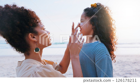 Mom, girl and sunscreen for face at beach for uv protection, care and love on vacation in summer. Mother, child and application for spf lotion, skin and bonding with smile by sea on holiday in Brazil 126178211