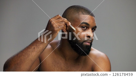 Beauty, skincare and serum with black man in studio for facial, grooming and dermatology. Cosmetics, glow and self care with person and oil dropper on gray background for hydration, hygiene or shine 126178459