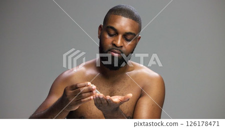 Facial, skincare and serum with black man in studio for beauty, grooming and dermatology. Cosmetics, glow and self care with person and dropper on gray background for hydration, hygiene and shine 126178471