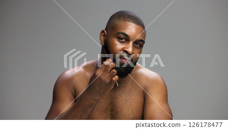 Man, portrait and comb beard in studio for grooming routine, detangle facial hair and self care maintenance. Mockup space, black person and cosmetics tool on gray background for styling and hygiene Man, portrait and comb beard in studio for grooming routine, detangle facial hair and self care maintenance. Mockup space, black person and cosmetics tool on gray background for styling and hygiene 126178477