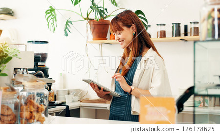 Barista, tablet and order with woman in cafe for research, digital inventory or restaurant supply checklist. Waitress, catering review and small business owner with person in coffee shop for menu Barista, tablet and order with woman in cafe for research, digital inventory or restaurant supply checklist. Waitress, catering review and small business owner with person in coffee shop for menu 126178625
