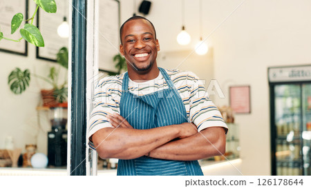 Portrait, smile and black man in coffee shop, arms crossed and hospitality industry with confidence. African person, business owner or entrepreneur with pride, welcome or entrance for cafe or waiter 126178644