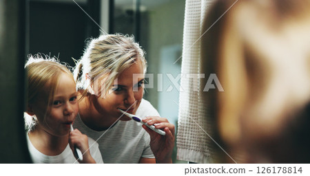 Mother, child and brushing teeth with mirror in bathroom for morning routine or cleaning mouth at home. Mom, daughter or kid with toothbrush for fresh breath, dental hygiene or oral care at house 126178814