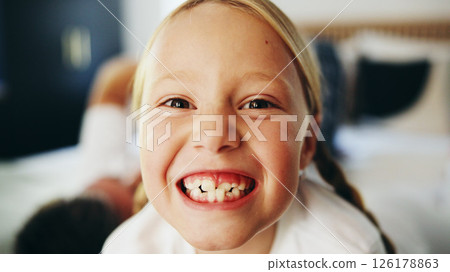 Happy girl, portrait and child on bed for weekend, morning or oral care in joy at home. Face, teeth or kid with smile in relax for dental hygiene, comfort or positive attitude in bedroom at house 126178863
