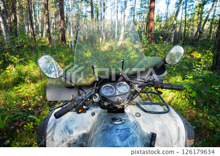 ATV Quad bike parked in a dense forest during a clear day exploring nature's beauty and adventure. All Terrain Vehicle outside 126179634