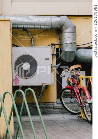 air conditioner on facade of building in southern hot country next to bicycle parking lot.  126179961