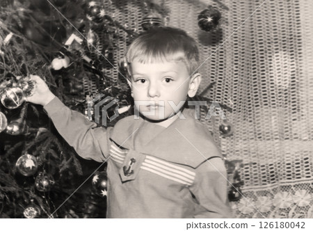Vintage portrait of a little boy near a Christmas tree. Retro photo from 1970. Vintage portrait of a little boy near a Christmas tree. Retro photo from 1970. 126180042
