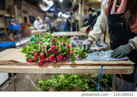 Rose flower seller preparing packaging floral bouquets at table for buyers and market delivery 126180081