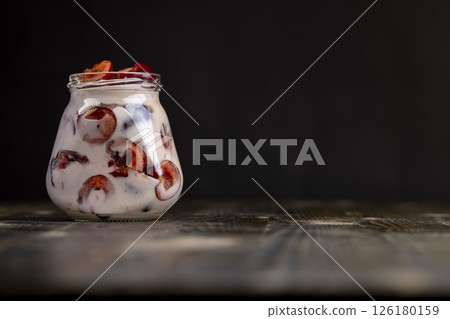 yogurt with cherry flavor and berry slices, jar with cherry yogurt with fresh red cherries closeup yogurt with cherry flavor and berry slices, jar with cherry yogurt with fresh red cherries closeup 126180159