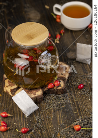 ingredients for tea with the rose fruits closeup, rosehip fruits in red and green tea on the table during cooking 126180164
