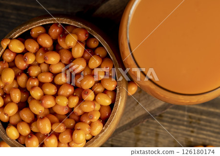 frozen orange sea buckthorn berries and a glass of sea buckthorn juice, a glass of natural orange juice and frozen sea buckthorn berries 126180174