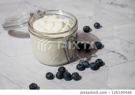 Glass jar with natural organic homemade yogurt and blueberries on table. Immunity-boosting ingredients. Concept of healthy eating breakfast of Greek yogurt. Fermenting superfood 126180486