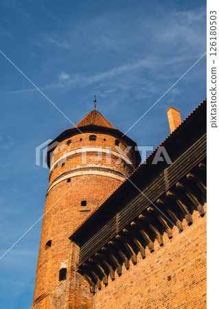 Old teutonic historical castle in Olsztyn Gothic Crusaders castle, tourist attraction of eastern Poland. Yellow orange brick wall with wooden decoration 126180503