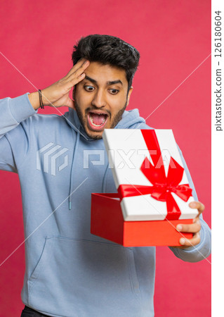 Excited Indian man receiving gift with red bow opening box celebrating surprise present happiness 126180604