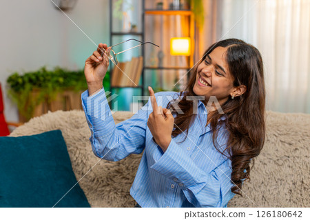 Indian woman laughing while searching for glasses on home sofa funny playful facial reaction Indian woman laughing while searching for glasses on home sofa funny playful facial reaction 126180642