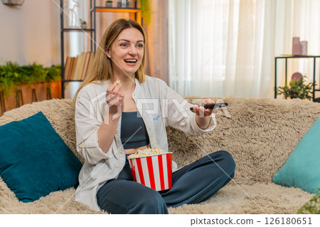 Adult woman laughing while watching comedy on television at home, joyful expression and relaxed mood Adult woman laughing while watching comedy on television at home, joyful expression and relaxed mood 126180651