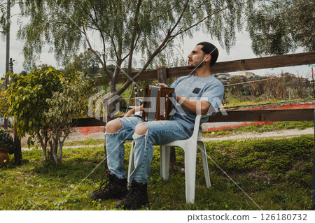 Man With Accordion Relaxing On A Chair Outdoor Man With Accordion Relaxing On A Chair Outdoor 126180732