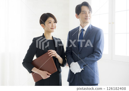 Smiling man and woman in business suits holding files Smiling man and woman in business suits holding files 126182408