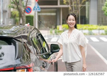 Female driver standing next to a car 126182567