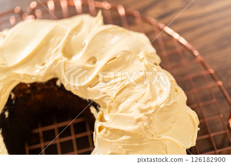 A gingerbread bundt cake being generously frosted with salted caramel frosting and topped with delightful gingerbread sprinkles. A gingerbread bundt cake being generously frosted with salted caramel frosting and topped with delightful gingerbread sprinkles. 126182900
