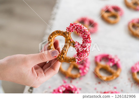 Freshly dipped and still glistening, these crunchy pretzels are lovingly adorned with pink chocolate and a scattering of colorful sprinkles, promising a feast for the senses. Freshly dipped and still glistening, these crunchy pretzels are lovingly adorned with pink chocolate and a scattering of colorful sprinkles, promising a feast for the senses. 126182906