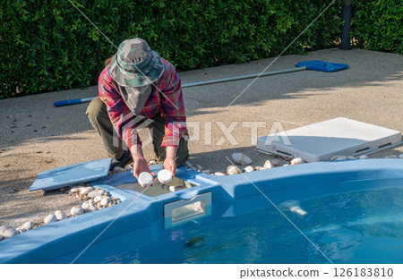 Technician holding chlorine tablets before throwing in swimming pool. Technician holding chlorine tablets before throwing in swimming pool. 126183810